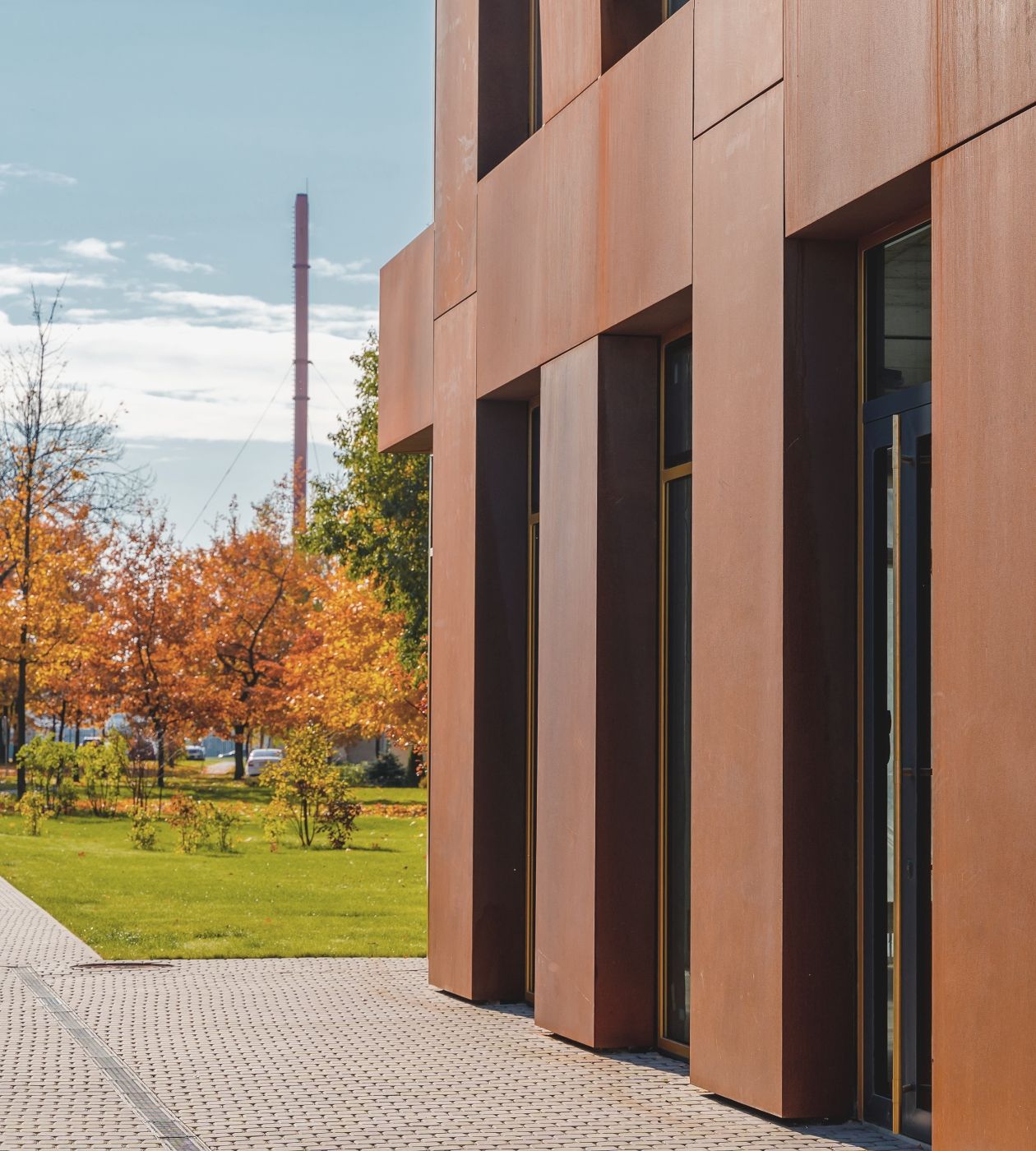 an entrance to a building clad in red, oxidised metal