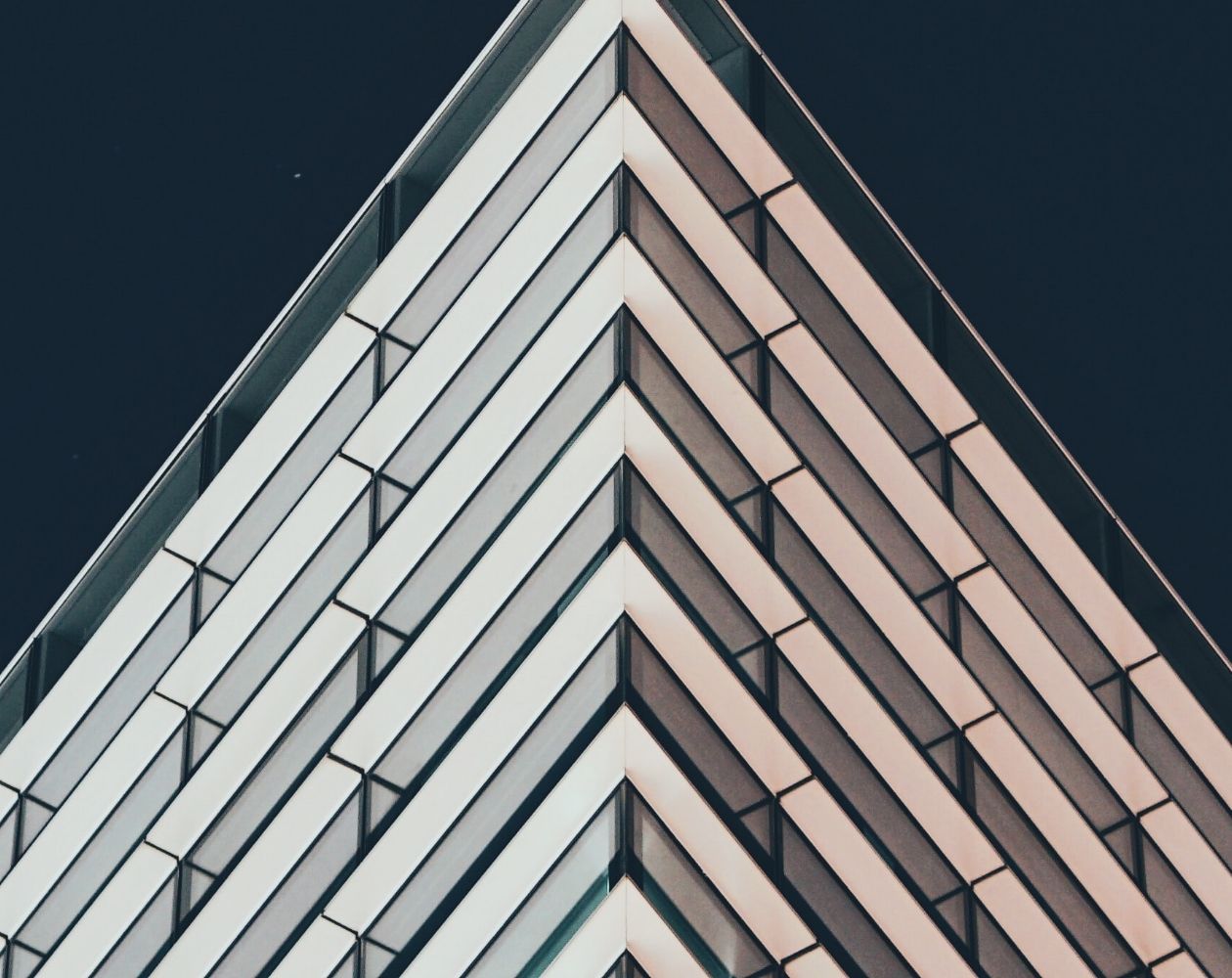 an arty shot of a high rise building taken from the bottom corner of the building looking upwards. it makes the building look like the top of an upward facing arrow